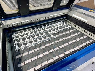 A close-up view of a laser engraving machine recently finished engraving white/black Ritchey ear tags.